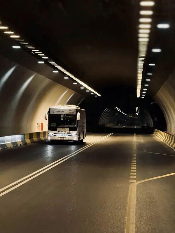 Passenger bus driving through a lit road tunnel near Makkah